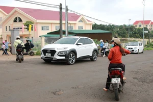 Một em học sinh đi xe đạp điện, phóng nhanh, tạt ngang đầu ô tô màu trắng để vào cổng tạm.(Ảnh: TT).