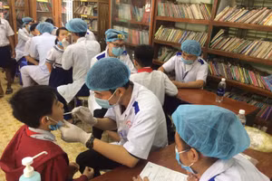Các bác sĩ thực hiện khám chữa răng cho học sinh