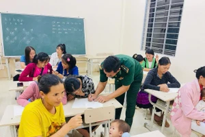 Thầy giáo quân hàm xanh tận tình hướng dẫn từng nét chữ đầu tiên cho học trò.