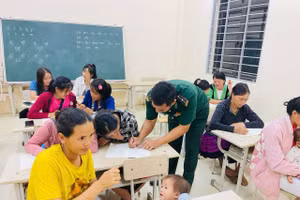 Thầy giáo quân hàm xanh tận tình hướng dẫn từng nét chữ đầu tiên cho học trò.