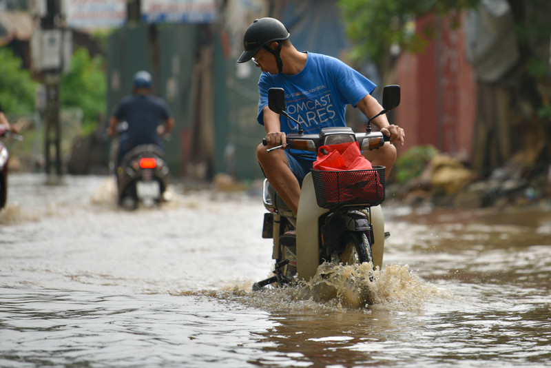 Người dân Hà Nội co chân trên xe máy lội qua đường ngập dù trời không mưa