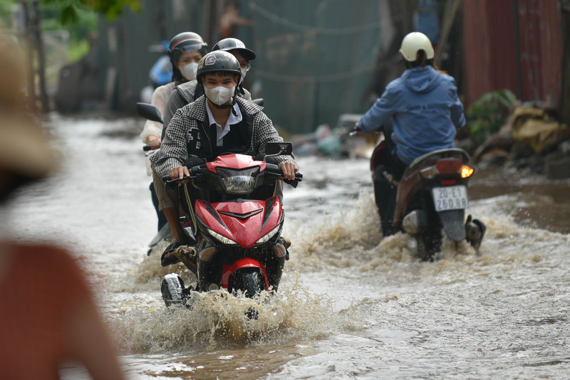 Người dân Hà Nội co chân trên xe máy lội qua đường ngập dù trời không mưa