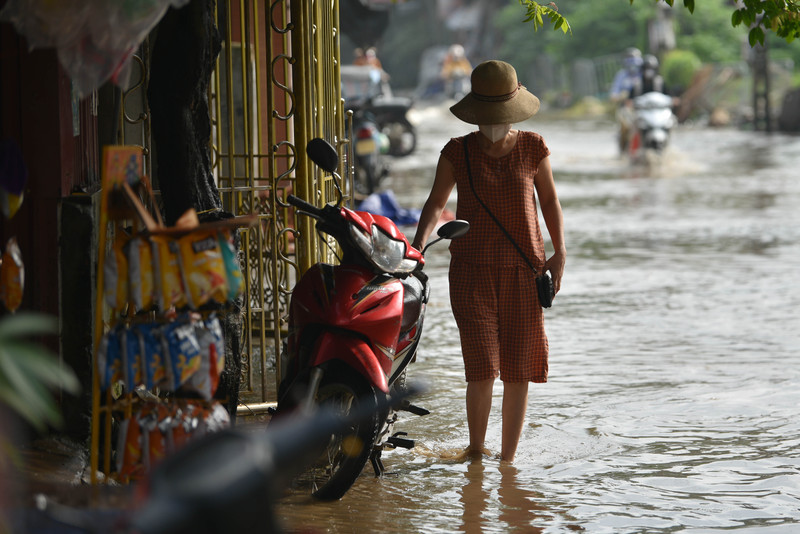 Người dân Hà Nội co chân trên xe máy lội qua đường ngập dù trời không mưa