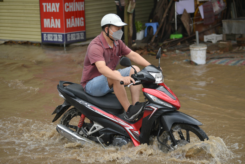 Người dân Hà Nội co chân trên xe máy lội qua đường ngập dù trời không mưa