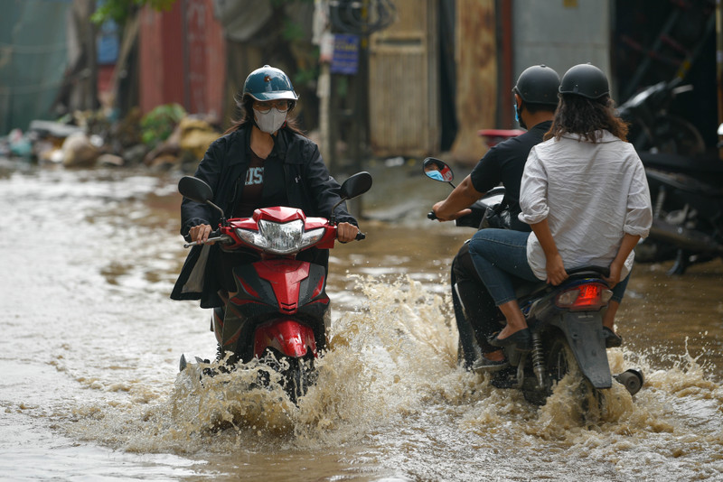 Người dân Hà Nội co chân trên xe máy lội qua đường ngập dù trời không mưa