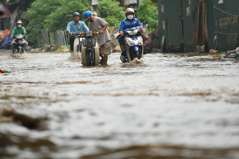 Người dân Hà Nội co chân trên xe máy lội qua đường ngập dù trời không mưa