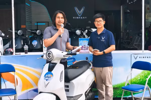 Anh Trịnh Huy Hiệu (bên trái) đang giới thiệu mẫu xe máy điện Evo Grand Lite cho khách hàng.
