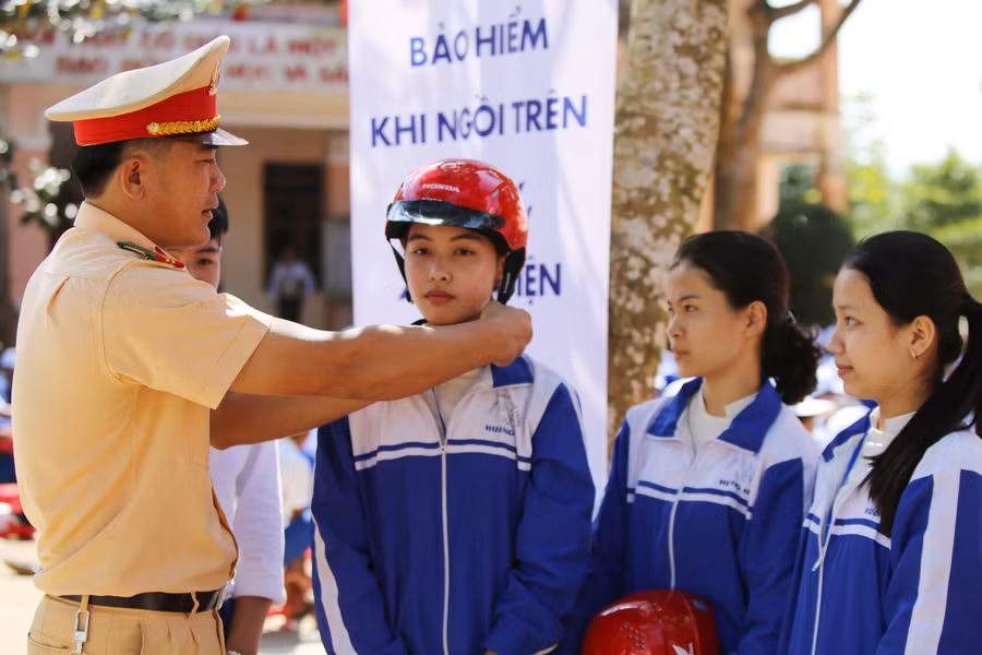 Lực lượng CSGT hướng dẫn cách đội mũ an toàn cho học sinh