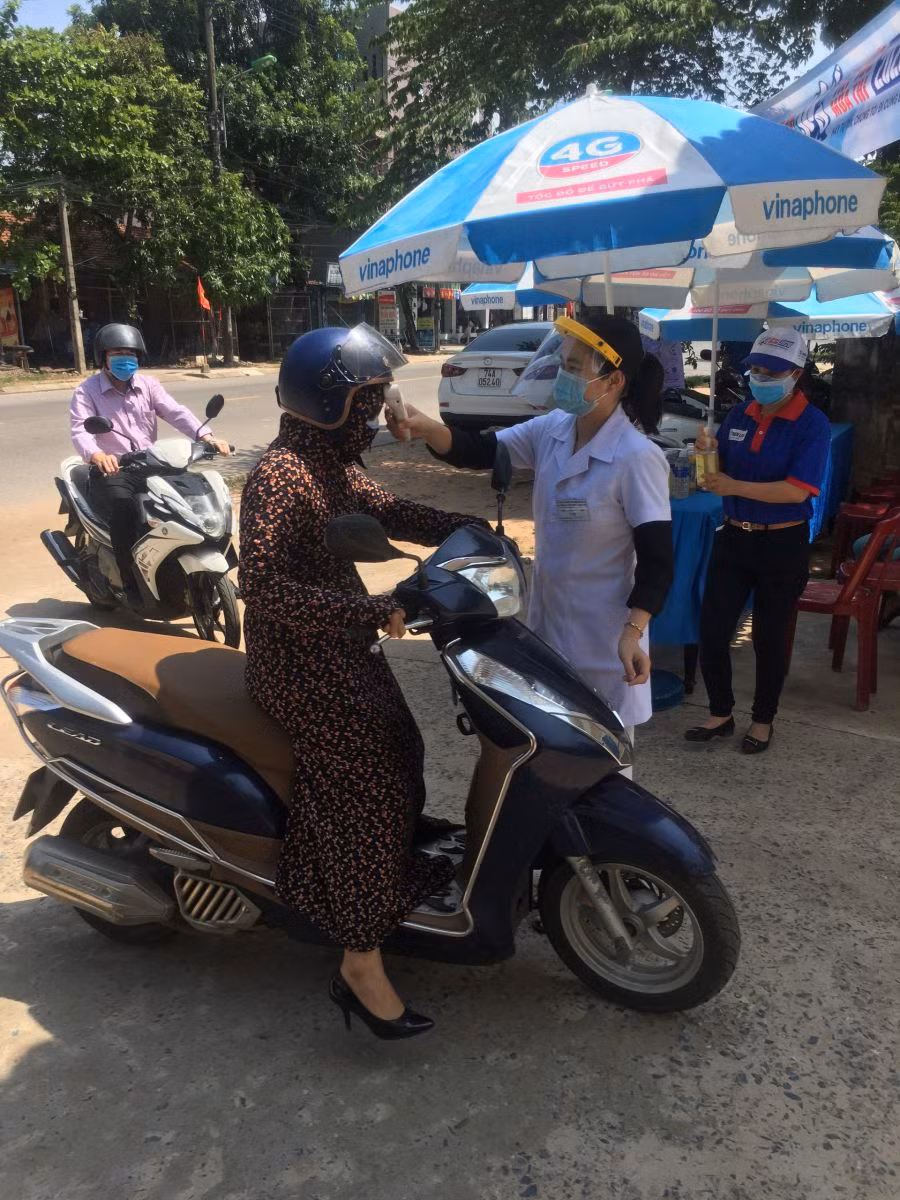 Kiểm tra thân nhiệt đối với cán bộ làm nhiệm vụ thi trước khi bước vào trường thi buổi chiều 3/9 .