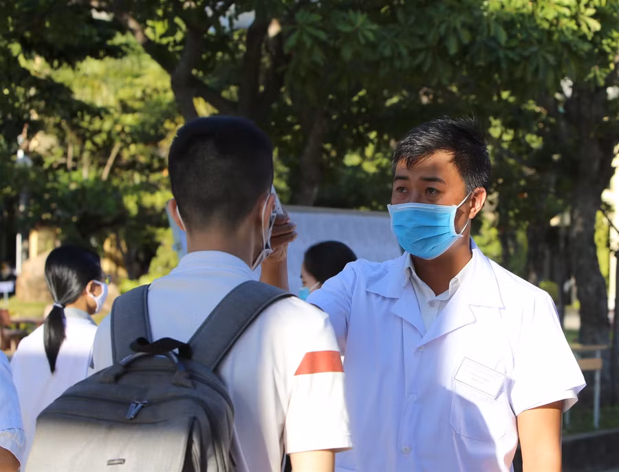 Đo thân nhiệt của học sinh trước khi vào trường lớp học.