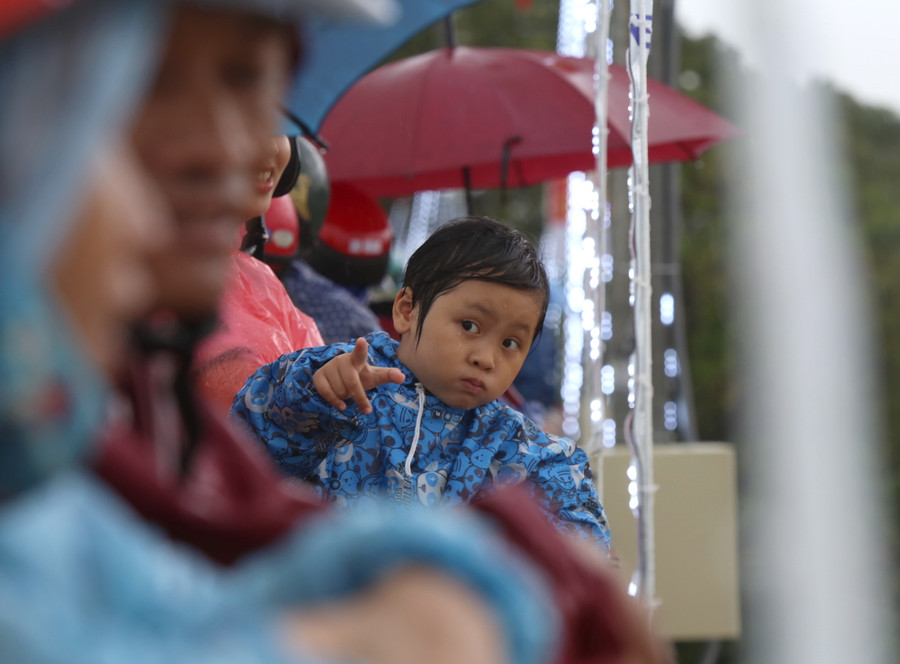 Một cháu nhỏ được bố mẹ đưa đi xem đua bơi thuyền truyền thống