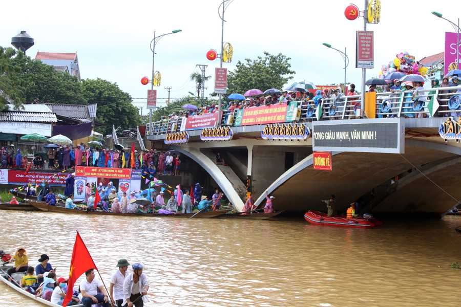 Người dân đứng trên cầu, dưới thuyền cổ vũ và chờ đoàn đua đi qua.