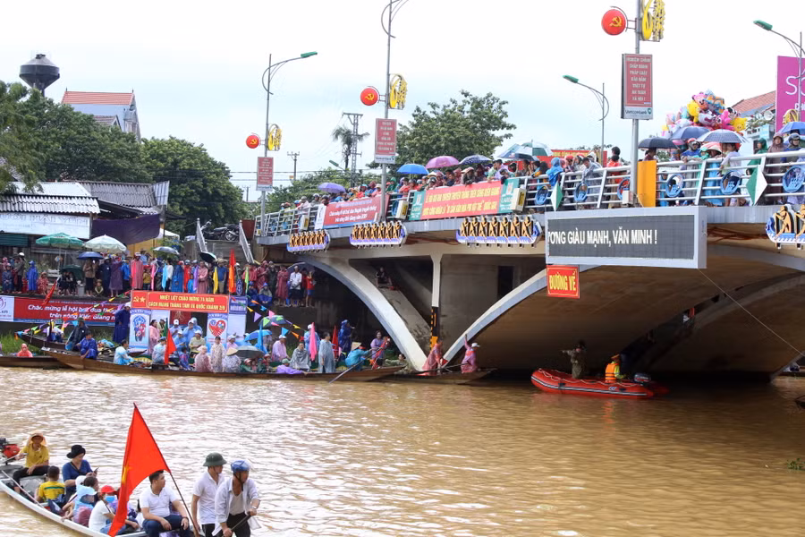 Người dân đứng trên cầu, dưới thuyền cổ vũ và chờ đoàn đua đi qua.