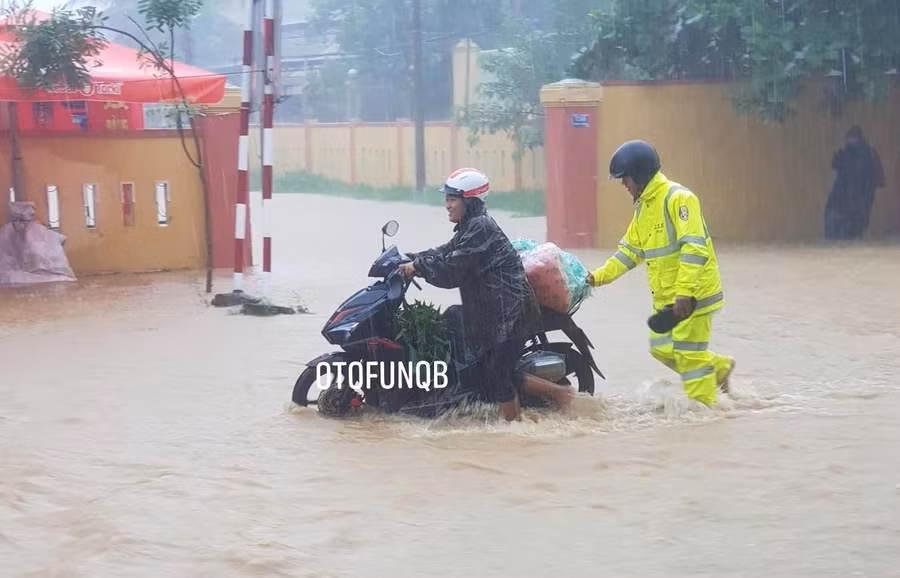 Lực lượng CSGT công an Lệ Thuỷ hỗ trợ người dân đi qua vùng ngập nước tại huyện Lệ Thuỷ (Ảnh OTOFUN QB)