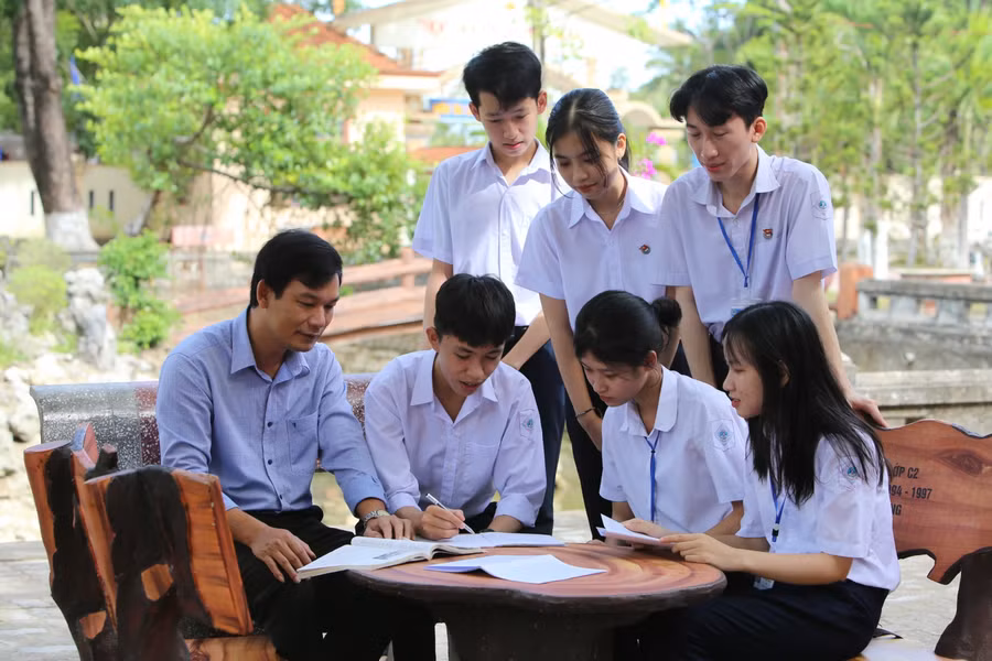 Tuần Kiệt cùng thầy giáo và bạn bè trao đổi bài vở trong giờ giải lao