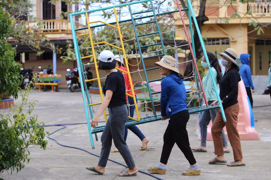 Các giáo viên mầm non di chuyển đồ chơi ngoài trời của trẻ để chống bão