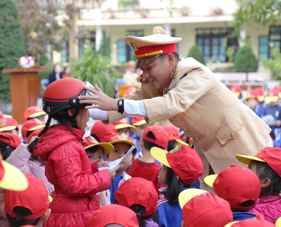 Cán bộ Phòng CSGT Công an tỉnh Quảng Bình hướng dẫn các em học sinh đội mũ bảo hiểm.