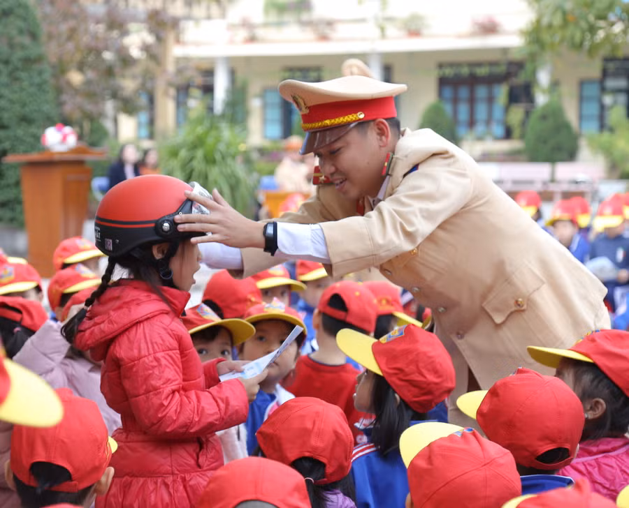 Cán bộ Phòng CSGT Công an tỉnh Quảng Bình hướng dẫn các em học sinh đội mũ bảo hiểm.