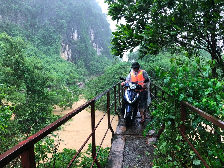 Người dân Minh Hoá men theo cầu máng vượt lũ trở về nhà (Ảnh baoquangbinh.vn)