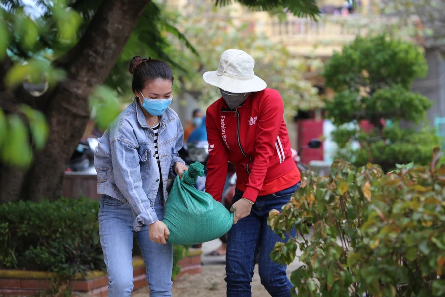 Giáo viên Trường Mầm non Nhân Trạch (Bố Trạch - Quảng Bình) chuyển những bao tải cát để đưa lên mái nhà chèn tấm lợp để tránh bị tốc mái.