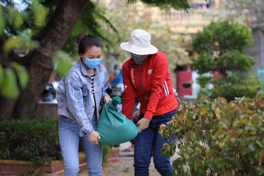 Giáo viên Trường Mầm non Nhân Trạch (Bố Trạch - Quảng Bình) chuyển những bao tải cát để đưa lên mái nhà chèn tấm lợp để tránh bị tốc mái.