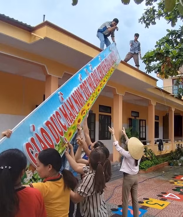 Phụ huynh cùng những cô giáo mầm non trường Mầm Non Quảng Thuận (Tx Ba Đồn - Quảng Bình) dỡ bảng hiệu tránh bão lũ.