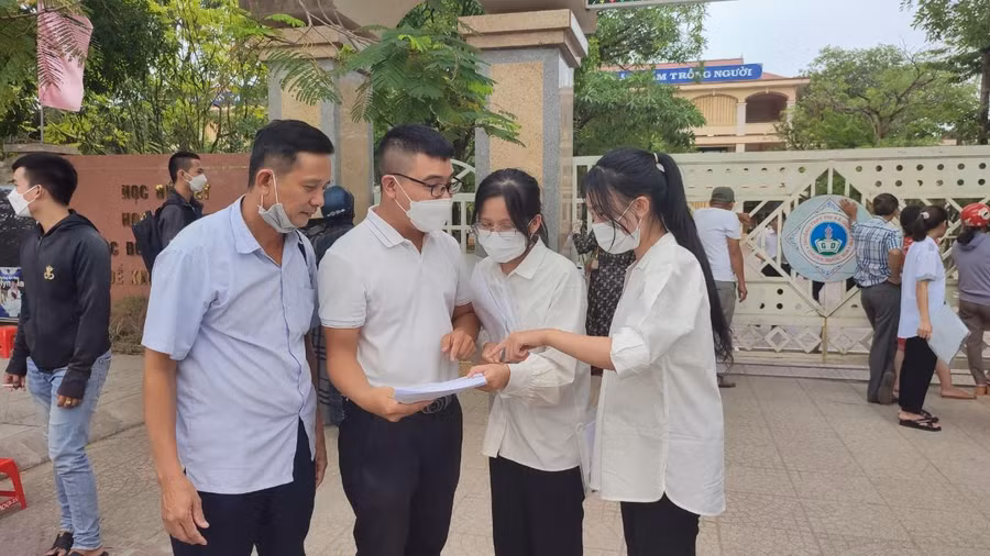 Các thí sinh nán lại trước cổng điểm thi để giải đề thi Toán.