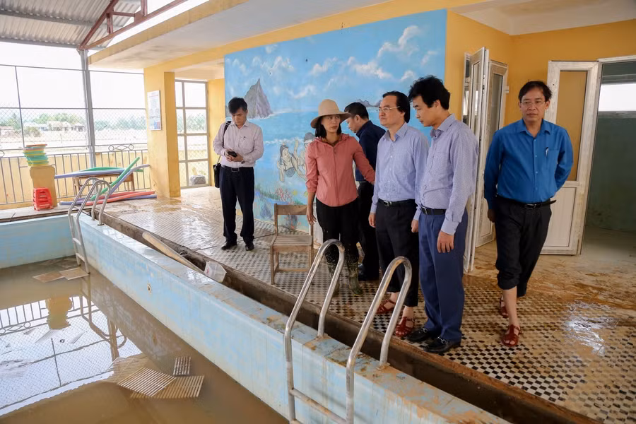 Bộ trưởng Phùng Xuân Nhạ nghe báo cáo về thiệt hại cơ sở vật chất của nhà trường sau cơn lũ.