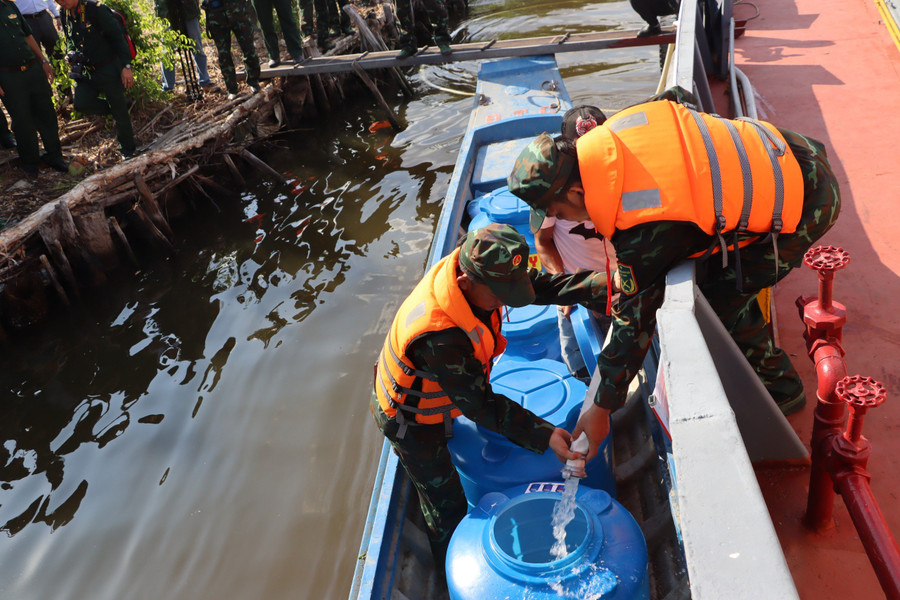 Cán bộ, chiến sĩ Quân khu 9 truyền nước ngọt vào dụng cụ trữ nước cho người dân.
