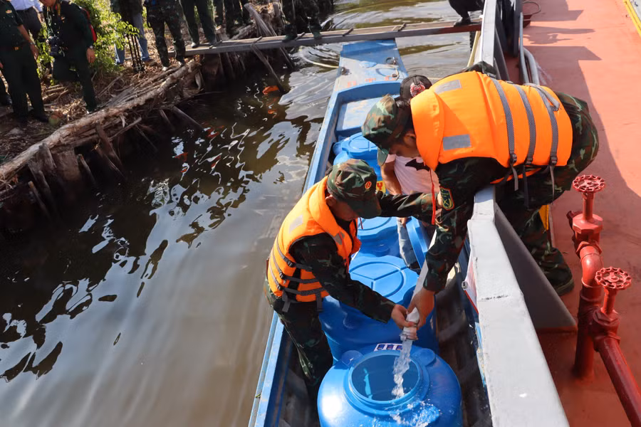Cán bộ, chiến sĩ Quân khu 9 truyền nước ngọt vào dụng cụ trữ nước cho người dân.