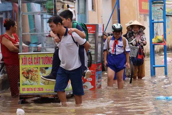 Học sinh và phụ huynh vất vả di chuyển khi triều cường dâng cao.
