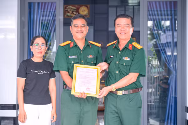 Đại tá Nguyễn Việt Thắng (phải) trao quyết định bàn giao nhà đồng đội cho gia đình Thiếu tá QNCN Liêu Đạt.