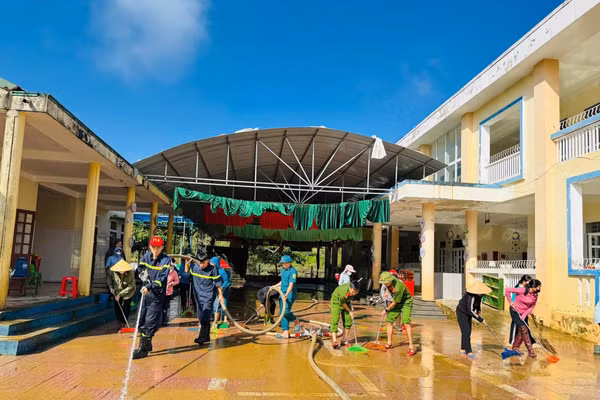 Lực lượng chức năng hỗ trợ dọn dẹp trường học sau mưa lũ.
