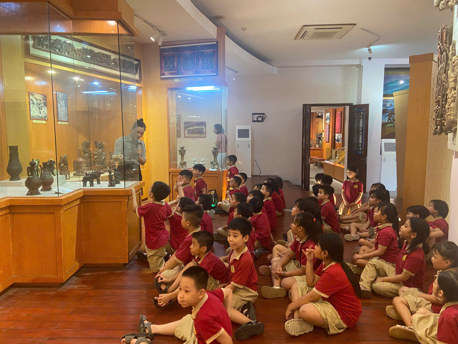 Học sinh Trường Tiểu học Hồ Tùng Mậu (Nam Định, Ninh Bình) chăm chú lắng nghe hướng dẫn viên giới thiệu hiện vật tại bảo tàng trong một buổi học trải nghiệm thực tế. anh-3.jpg
