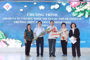 Đại diện Hội Cựu giáo chức nhà trường tặng hoa cho đại diện cựu học sinh tại chương trình. 