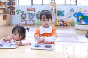 Trẻ ở lớp Nhà trẻ D4 tham gia vận động tinh bằng việc chuyển hạt bằng thìa.