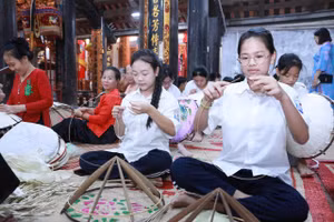 Các em học sinh được các nghệ nhân truyền nghề làm nón lá làng Chuông. Ảnh: Đình Tuệ.
