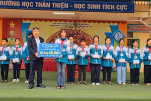 Đại diện gia đình bà Ngô Thùy Diễm - Việt kiều đang sinh sống tại Thụy Sĩ tặng quà cho học sinh nghèo của Trường THCS Hải Xuân.