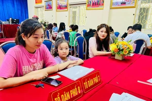 Phụ huynh đưa con tới trường để nhờ cán bộ giáo viên hướng dẫn đăng ký tuyển sinh trực tuyến vào lớp 1.