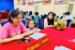 Phụ huynh đưa con tới trường để nhờ cán bộ giáo viên hướng dẫn đăng ký tuyển sinh trực tuyến vào lớp 1.