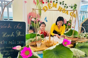 Cô giáo hướng dẫn trẻ 5 tuổi tại Trường Mầm non An Khánh B (Hà Nội) các bước để ướp chè sen. Ảnh: Khôi Nguyên.