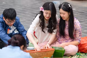 Các em học sinh cùng nhau trải nghiệm làm bánh chưng Tết tại sân trường.