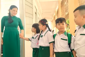 Học sinh được giáo viên chào đón trước cửa lớp.