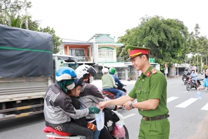 Cán bộ, chiến sĩ Công an phát nước suối và khăn lạnh cho người dân về quê nghỉ lễ.