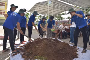 Sinh viên Trường Đại học Trà Vinh hướng dẫn bà con làm phân hữu cơ. Ảnh: Bình An