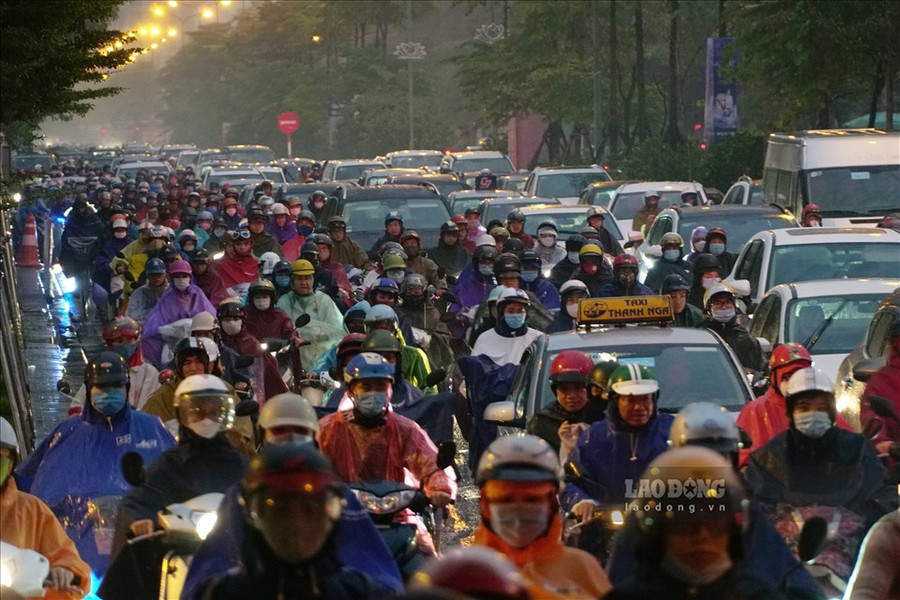 Người dân đội mưa, nhích từng cm trong giờ tan tầm. Ảnh: Tạ Quang.