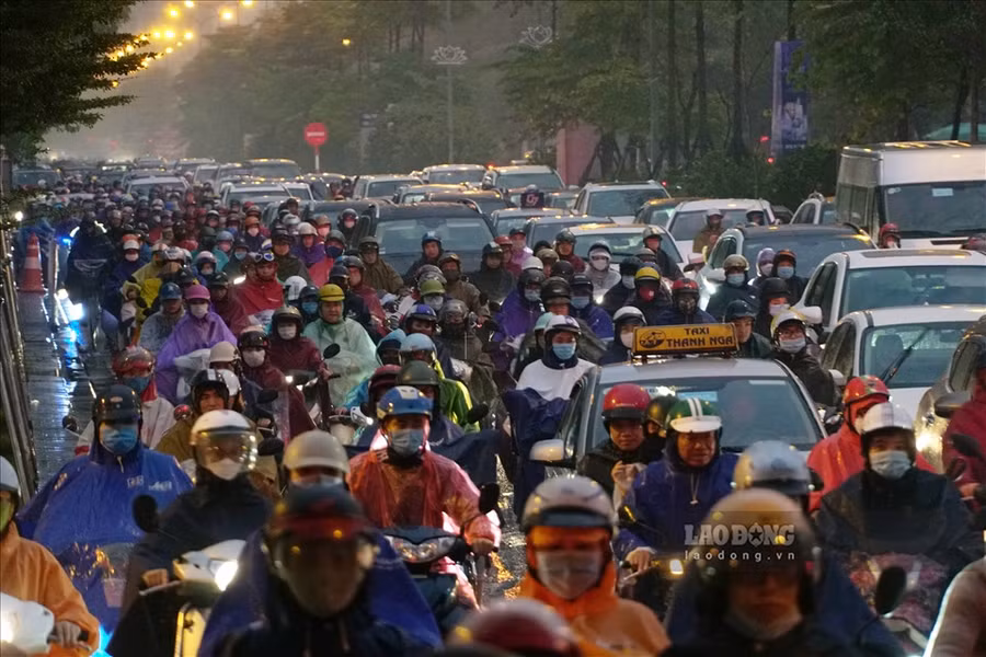 Người dân đội mưa, nhích từng cm trong giờ tan tầm. Ảnh: Tạ Quang.