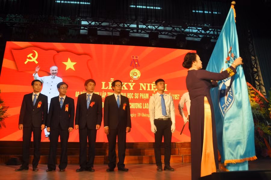 Thứ trưởng Nguyễn Thị Nghĩa gắn Huân chương Lao động hạng Ba vào lá cờ truyền thống Trường ĐHSP Huế