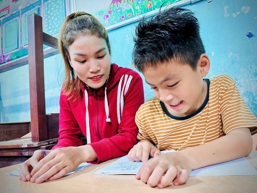 Học viên Cái Thị Thảo được con trai dò bài trong giờ giải lao của lớp xóa mù chữ. 554232799-1084868050392718-618139416917227186-n.jpg