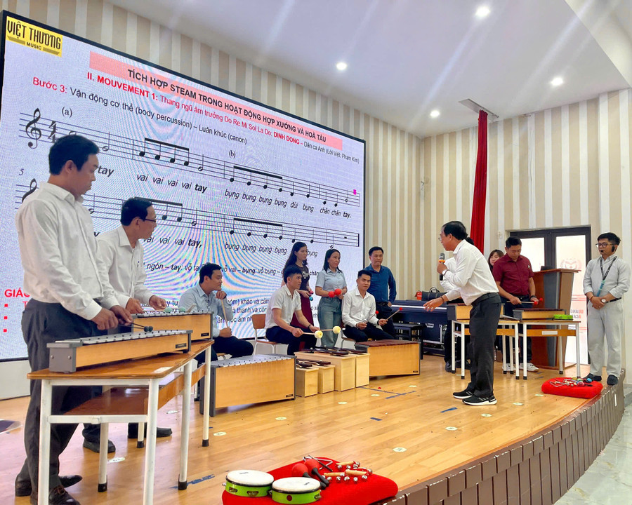 Giáo viên âm nhạc thực hành với các loại nhạc cụ để tổ chức hoạt động hòa tấu đơn giản tại lớp tập huấn. 